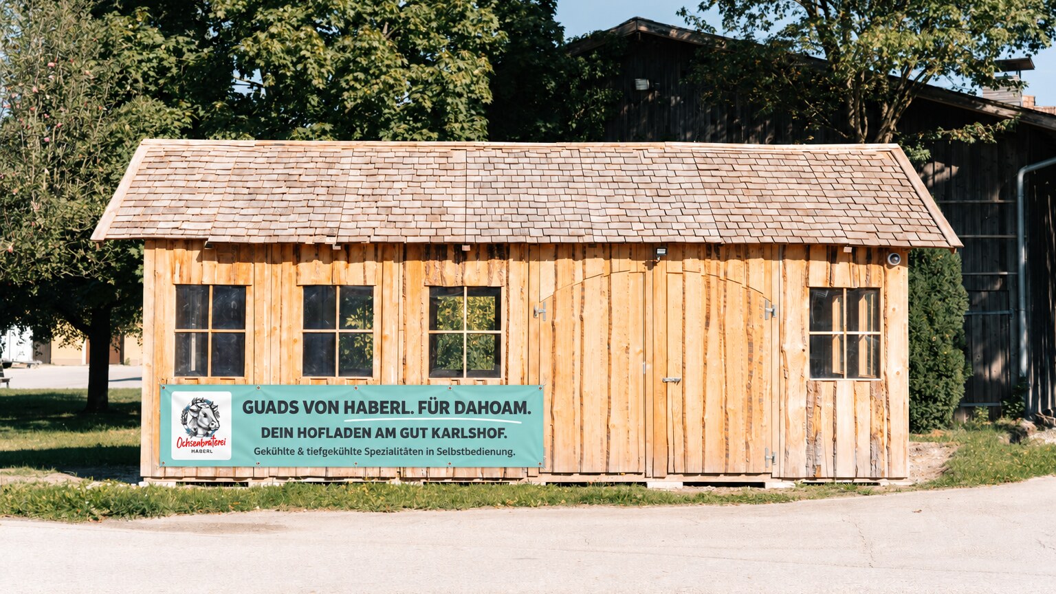 Holzhütte auf Gut Karlshof mit türkisfarbenem Banner.